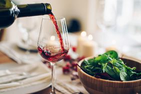 Red wine being poured into the glass at the table