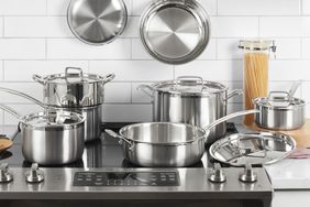 Set of metal pots and pans displayed on an induction cooktop in front of a white tile backsplash