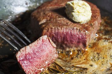 Close up of a steak cooking in butter.