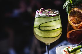 A cucumber cocktail on a counter with other drinks.