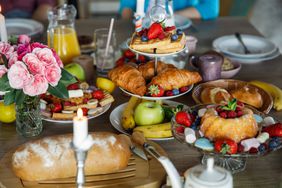 Delicious waffles, cake, croissants, fresh berry fruits and other tasty foods served on a table for friends to enjoy during brunch. 