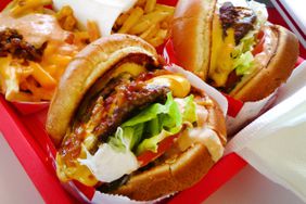 Two hamburgers and orders of fries on a red tray. 