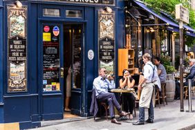 Parisians and tourists enjoy food and drinks at the street french cafe.