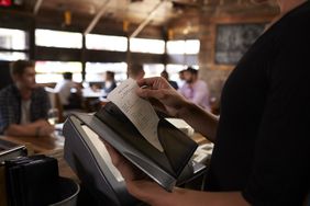 A server preparing the bill at a restaurant to be taken to a table.